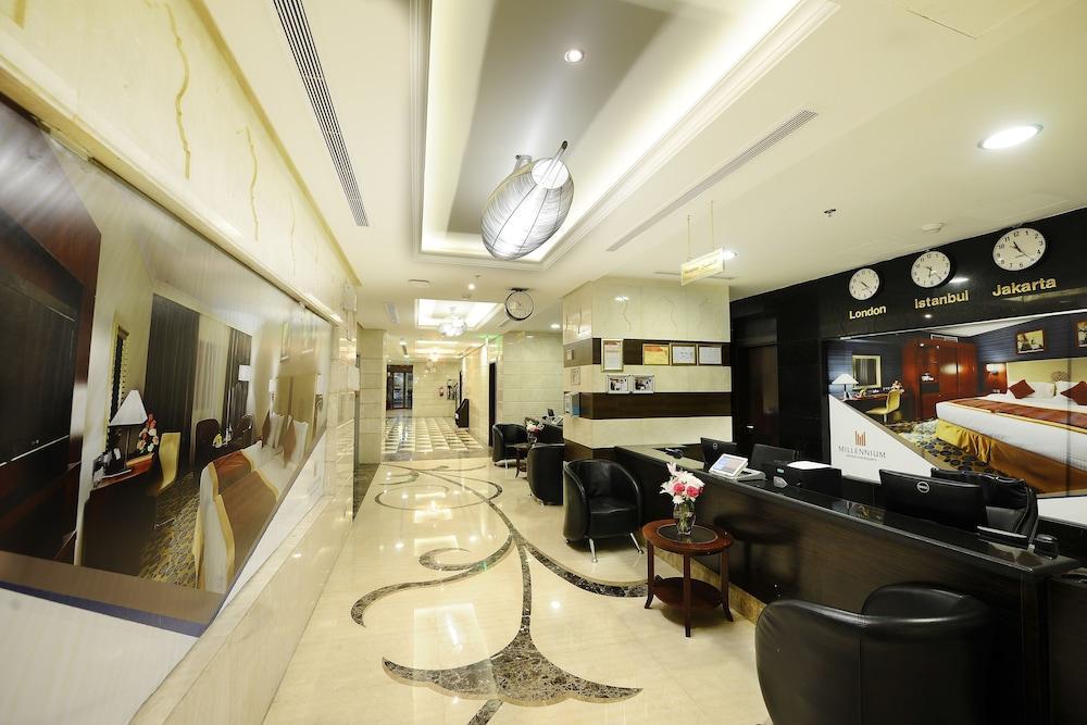 Al Aqeeq Madinah Hotel Medina Eksteriør billede The photo shows the interior of a hotel lobby or reception area. It features a sleek, modern design with elegant marble flooring, decorative lighting fixtures on the ceiling, and a sophisticated color scheme. There are comfortable black seating areas